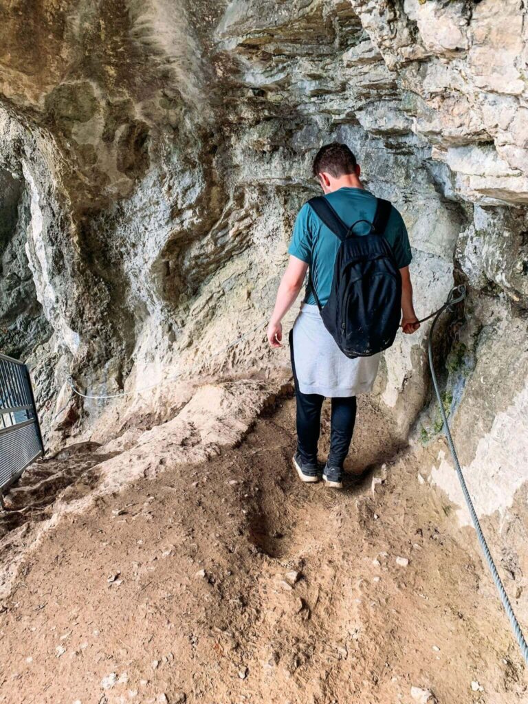 A man descending a path at the top of Cascade d'Angon.