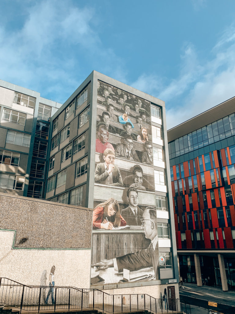 A mural on the side of a building featuring Strathclyde University Students from past and present