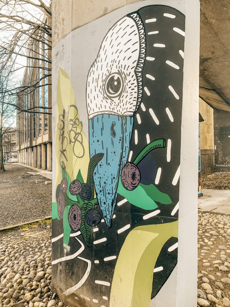 a mural of an abstract bird on a bridge post