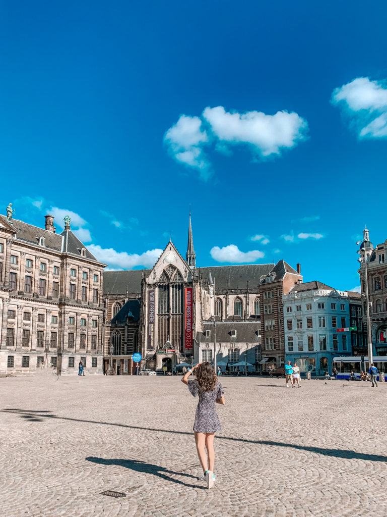 a girl standing in the middle of Dam square in Amsterdam