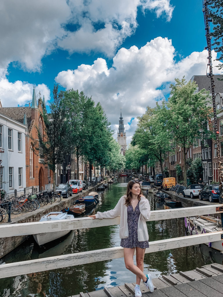A girl stands on Staalmeestersbrug, one of the best photo spots in amsterdam which looks down a canal