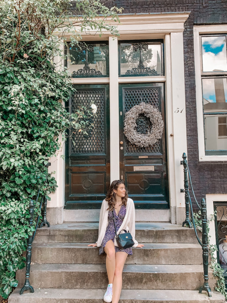a girl sitting on steps in front of a black door in Amsterdam