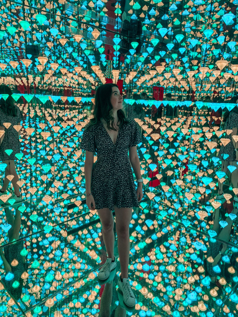 a girl stands in a light exhibition in the moco musueum in Amsterdam