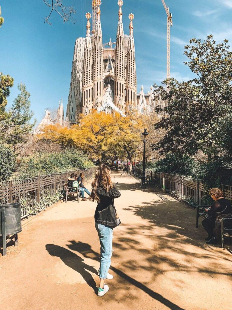 A girl standing in front of the Sagrada Familia in Barcelona.