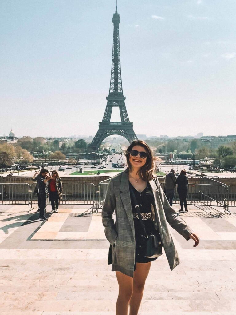 A girl smiles in front of the Eiffel Tower at Trocadero.