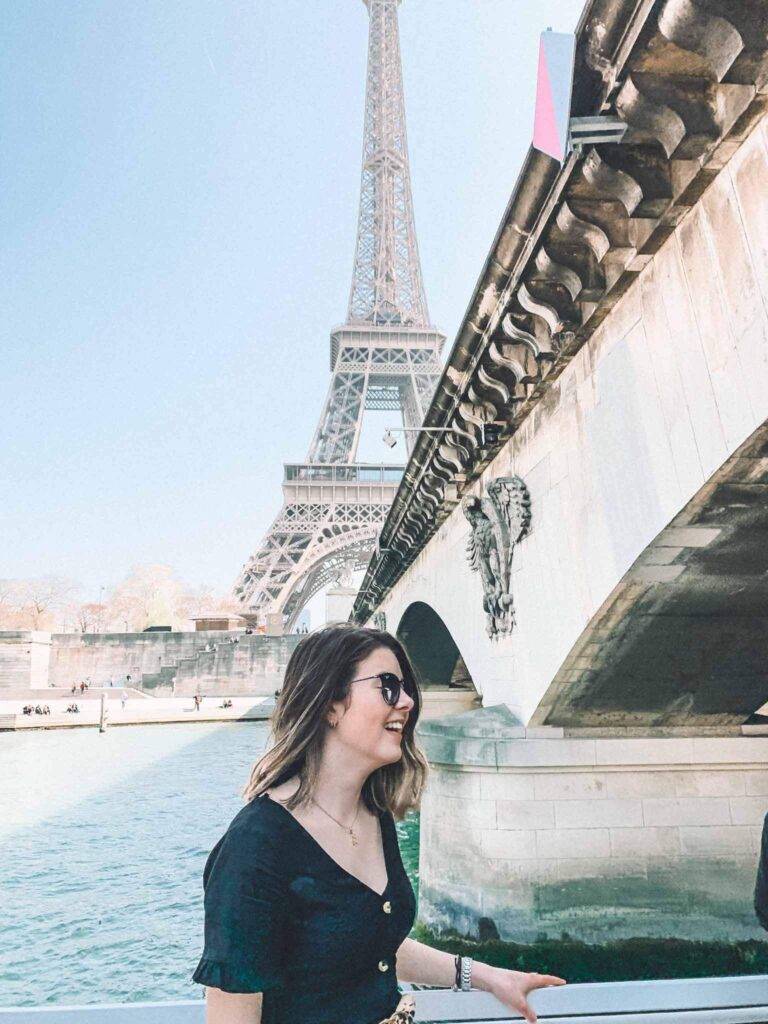 A girl on a river boat along the Seine riding past the Eiffel Tower.