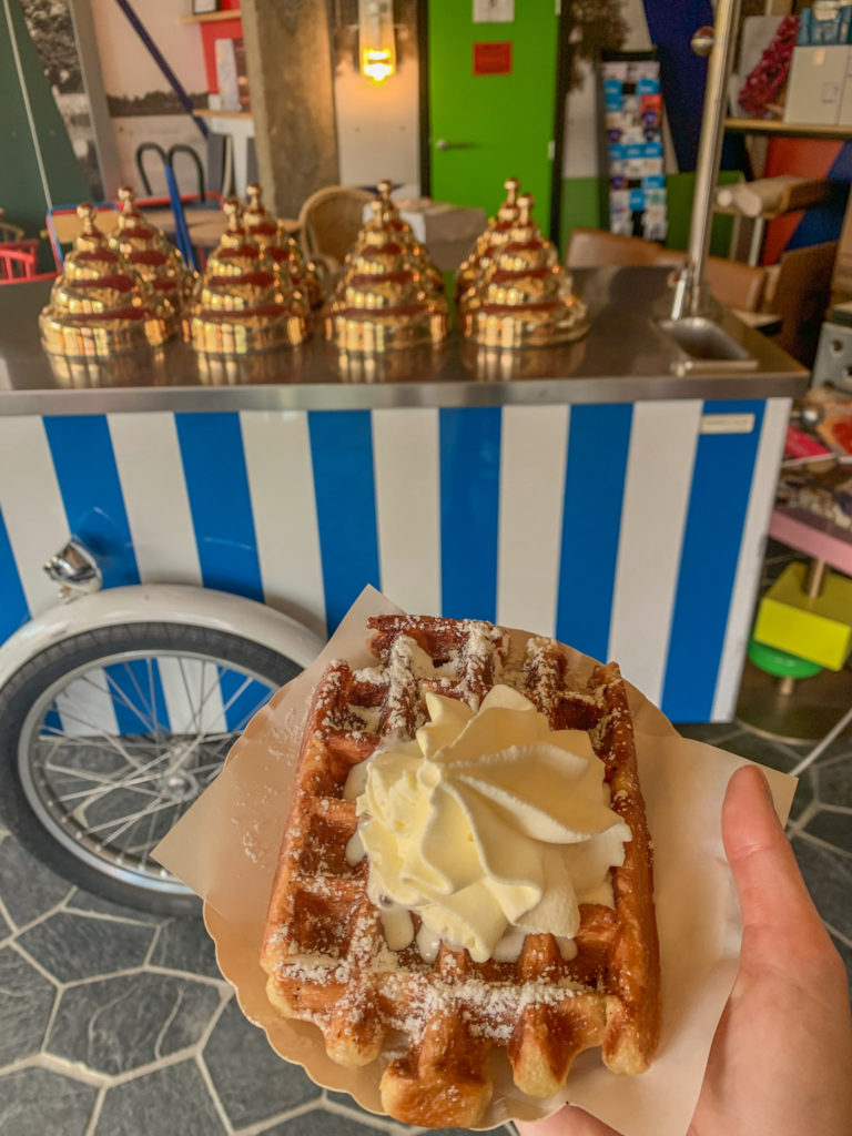 A Belgian waffle with cream from Gaston, Brussels, with an old fashioned ice cream cart in the background