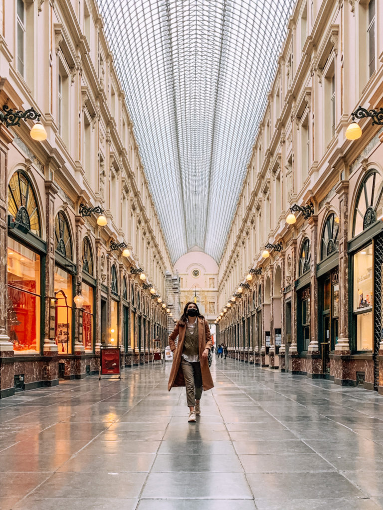 A girl walks and looks up through Galeries Royales Saint Hubert, a covered passage and arcade in Brussels