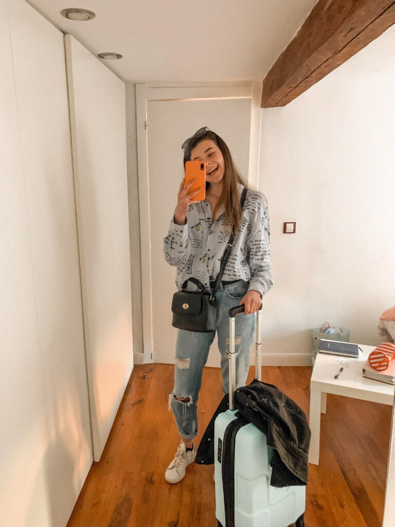 a girl stands with a carry-on suitcase