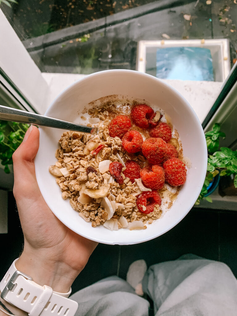 birdseye view of a bowl of granola, yoghurt, and raspberries