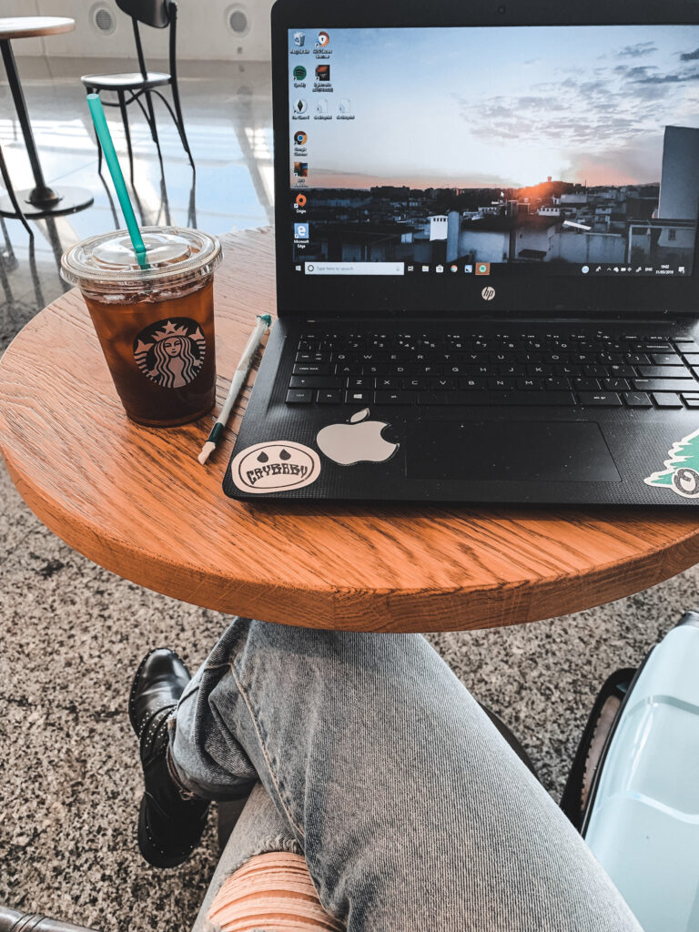 shot of a coffee table in an airport, with an iced coffee from Starbucks and an open laptop