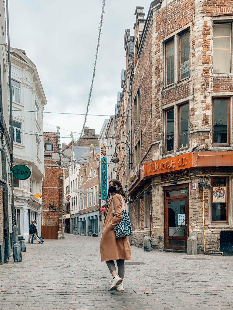 a girl walks along an empty Rue des Bouchers in the center of Brussels