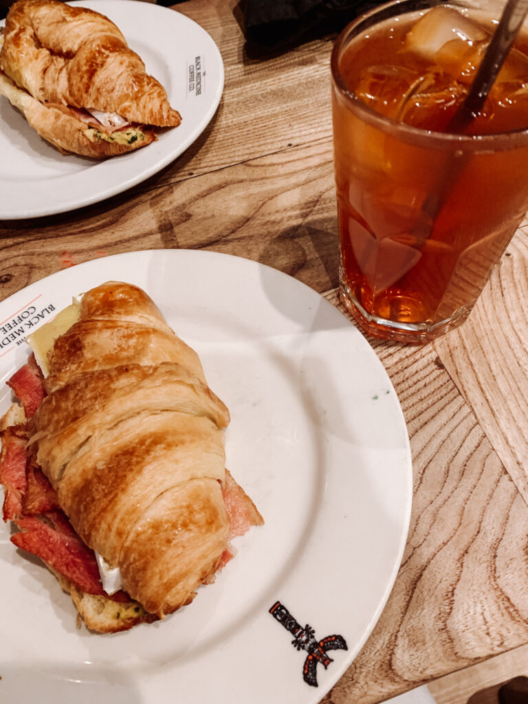 two filled croissants on plates and a glass of iced tea from Black Medicine coffee in Edinburgh