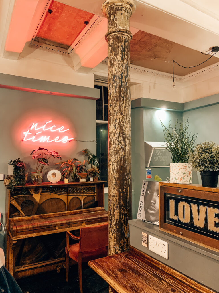 inside Lovecrumbs cafe with a neon sign, piano and countertop