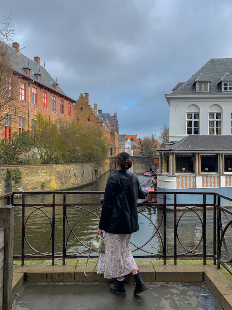 a girl faces away from the camera overlooking a Bruges canal