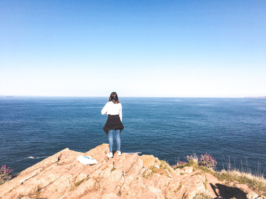 A girl stands on top of a cliff at the faro de Cabo mayor in Santander, Spain