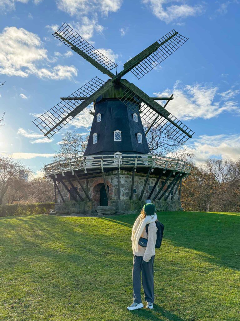 A girl looks up at a windmill in Slottsparken, Malmö