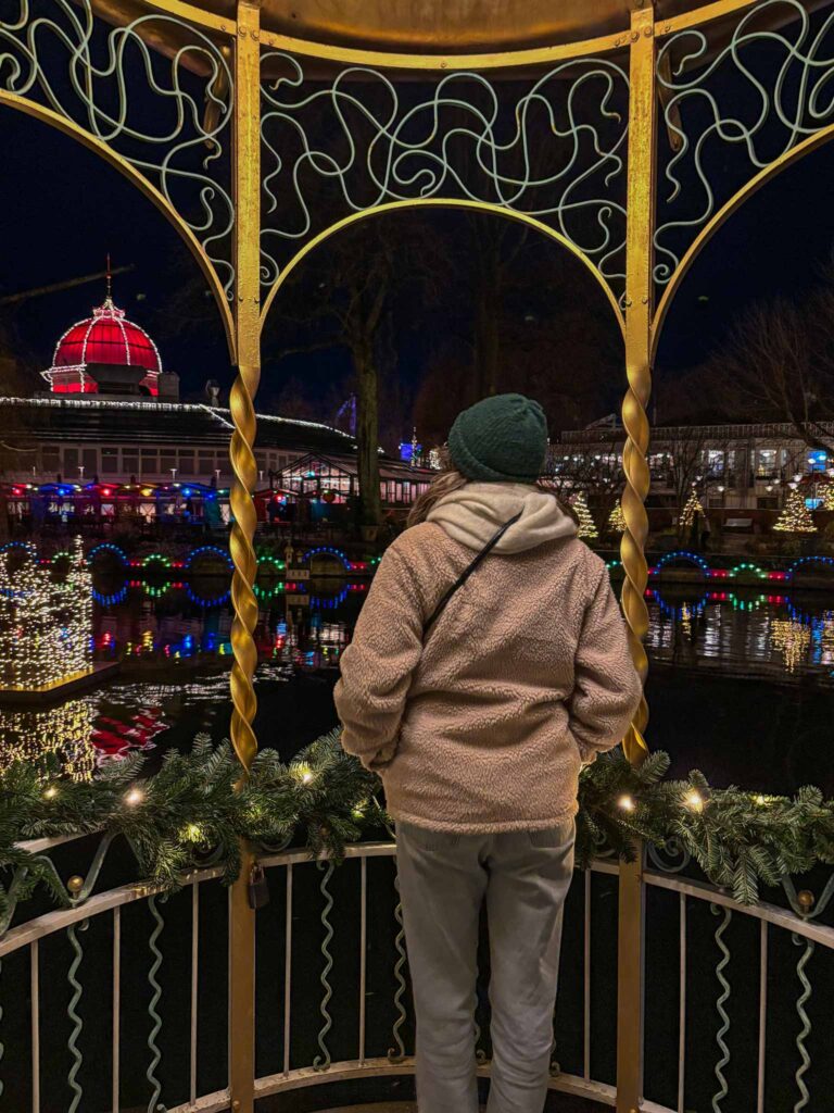 A girl stands in a small pavilion at night time, at Tivoli Gardens in Copenhagen
