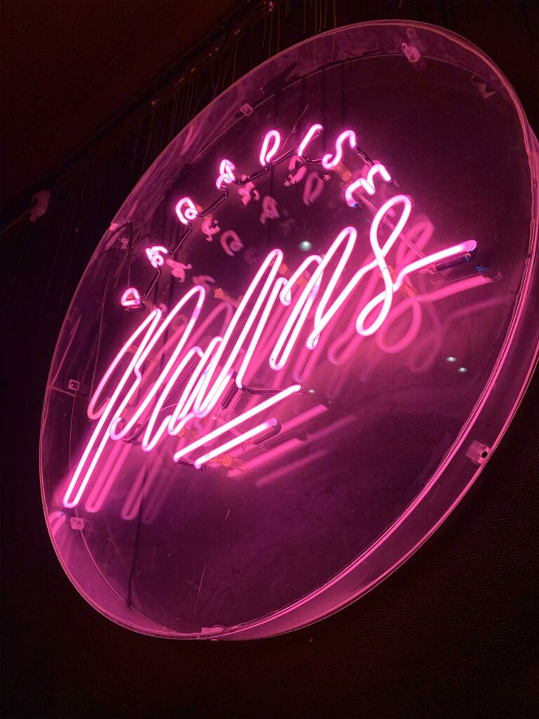 Pink neon sign reading Paradise Palms