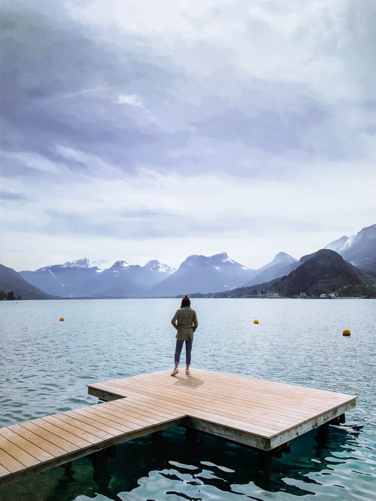Girl standing on a wooden pier over Lake Annecy in Talloires.